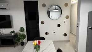 A modern kitchen with a marble countertop, a round mirror, and a potted plant.