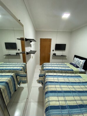 A bedroom with two beds, a TV on the wall, and a mirror.