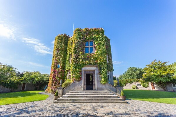 A castle-like building with a stone facade, a central entrance, and steps leading up to it.