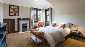 Ein Schlafzimmer mit einem großen Bett, einem Kamin, einem Schreibtisch und einem Fenster mit Vorhängen.