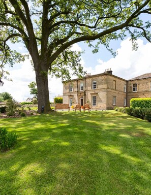 A large tree in front of a stone building with multiple windows and a well-maintained lawn. - Emley Woodhouse - Seven Bedroom Villa, Sleeps 17 (Emley)