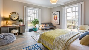 A bedroom with a large bed, a desk, a chair, a sofa, and a window. - Emley Woodhouse - Seven Bedroom Villa, Sleeps 17 (Emley)