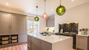 A modern kitchen with grey cabinets, a large island, and a black backsplash. - Emley Woodhouse - Seven Bedroom Villa, Sleeps 17 (Emley)