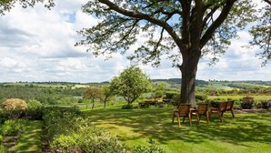 A garden with a large tree, a lawn, and a seating area with chairs. - Emley Woodhouse - Seven Bedroom Villa, Sleeps 17 (Emley)