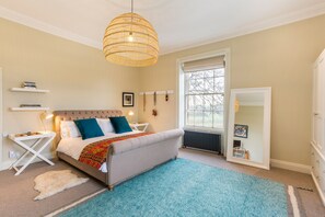 A bedroom with a bed, bedside tables, a hanging light fixture, a window, and a radiator. - Emley Woodhouse - Seven Bedroom Villa, Sleeps 17 (Emley)