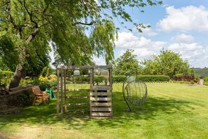 A playground with a wooden climbing structure, a swing, and a slide.