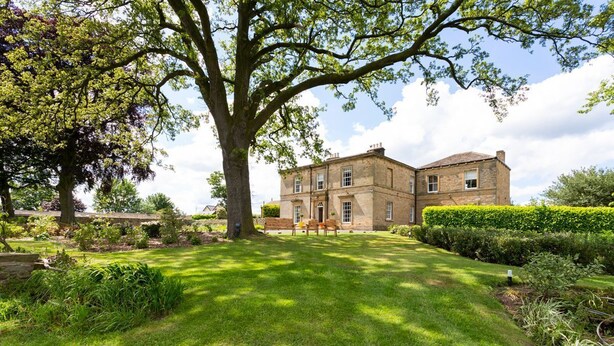 A large, two-story stone building with a well-maintained lawn and a large tree in the foreground. - Emley Woodhouse - Seven Bedroom Villa, Sleeps 17 (Emley)