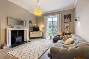 A living room with a fireplace, sofa, rug, and a television.