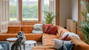 A cozy living room with a sectional sofa, a small round table, and a dog.
