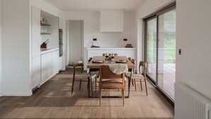 Una cocina moderna con comedor, armarios blancos y un ventanal grande.
