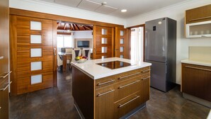 A modern kitchen with wooden cabinetry, a central island, and a built-in refrigerator. - Villa Princesa - Four Bedroom Villa, Sleeps 8 (Puerto Calero)