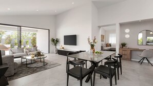 A modern living space with a dining area, a sofa set, a flat-screen TV, and a kitchen area with a wooden countertop and a mirror.