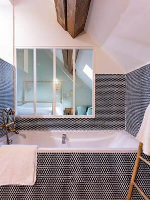 A bathroom with a large mirror, a bathtub, and a shower area.