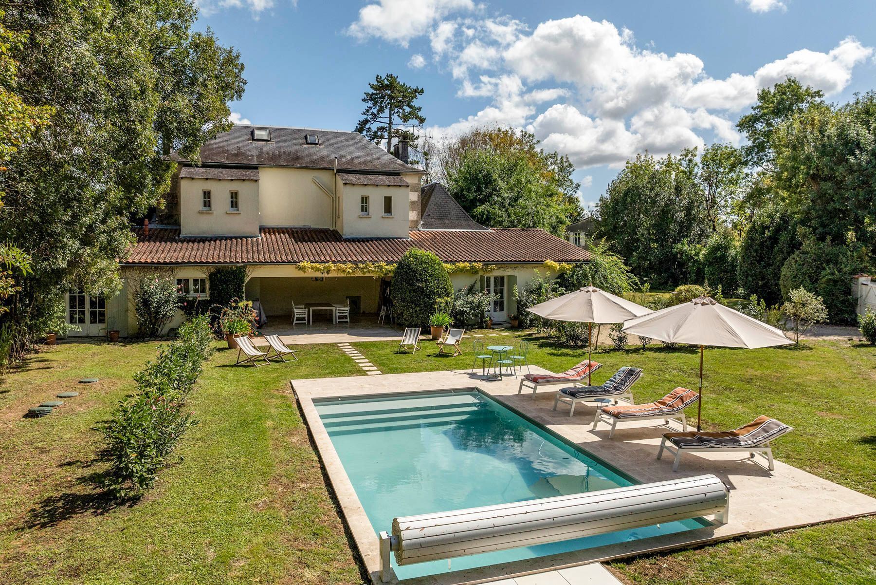Een groot huis met een zwembad, terras en tuin.