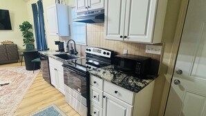 Una cocina moderna con armarios blancos, una estufa negra y encimera de granito.