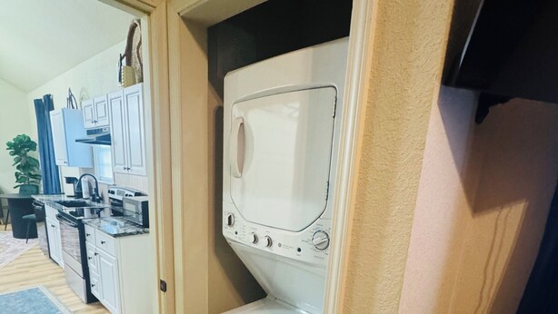 Una cocina compacta con armarios blancos, horno integrado y lavadora.