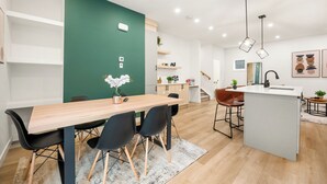 Una cucina moderna con isola centrale, sedie nere e un tavolo da pranzo in legno.