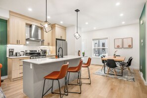 Una cocina moderna con armarios de madera, electrodomésticos de acero inoxidable y una isla central con taburetes de bar.