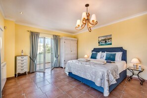 Une chambre à coucher comprenant un lit, des lampes de chevet, une commode, une armoire et une vue sur l’extérieur.