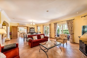 A spacious living room with a red sofa, a glass coffee table, and a fireplace. - Villa Palmeira - Four Bedroom Villa, Sleeps 8 (Carvoeiro)