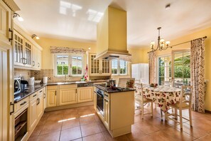 A spacious kitchen with a central island, built-in cabinetry, and a dining area with a table and chairs. - Villa Palmeira - Four Bedroom Villa, Sleeps 8 (Carvoeiro)