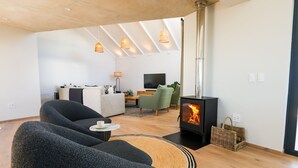 Una sala de estar moderna con chimenea, dos sofás, televisor y comedor.