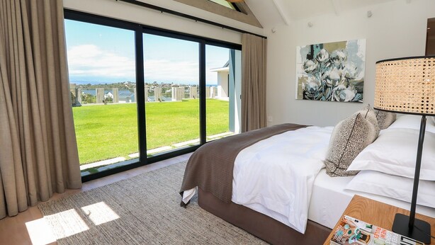 Habitación de hotel con una cama grande, vistas a un paisaje verde y un cuadro en la pared.