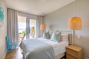 A bedroom with a bed, bedside table, and a view of the outdoors. - Busisiwe House - Four Bedroom Apartment, Sleeps 10 (Plettenberg Bay)