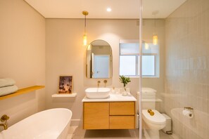 A modern bathroom with a freestanding bathtub, a vanity with a mirror, and a toilet. - Busisiwe House - Four Bedroom Apartment, Sleeps 10 (Plettenberg Bay)