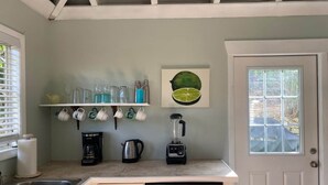 A kitchen with a sink, coffee maker, blender, and a shelf with cups and glasses. - Lime Time (Coral Bay, St John)