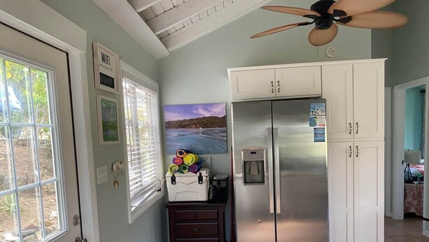 A kitchen with a stainless steel refrigerator, a water dispenser, and a window with blinds. - Lime Time (Coral Bay, St John)