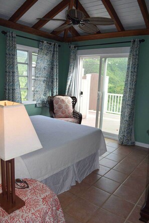 Ein Schlafzimmer mit einem Bett, einem Sessel, einer Lampe und Blick auf einen Balkon.