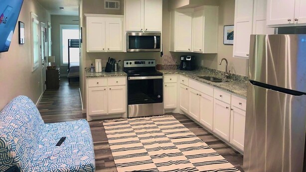 Una cucina compatta con mobili bianchi, elettrodomestici in acciaio inossidabile e un tappeto decorato.