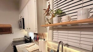 Een keuken met een granieten aanrecht, een roestvrijstalen spoelbak en een raam met jaloezieën.