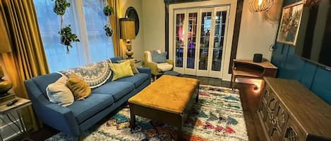 A living room with a blue sofa, a wooden coffee table, a patterned rug, and a wooden cabinet.