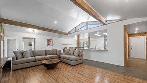 A spacious living room with a large sectional sofa, a coffee table, and a wooden floor. - Its not Unusual MidTerm Rental (Arlington)
