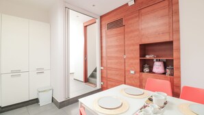 Cocina moderna con armarios blancos, encimera blanca y comedor con una mesa dispuesta para cuatro.