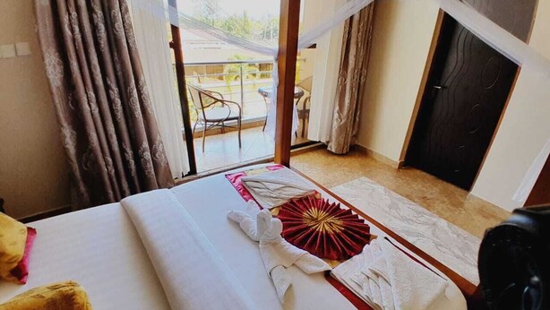 Una camera d'albergo con un letto, vista sul balcone esterno e una porta.