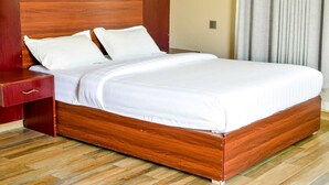Un letto di legno con biancheria da letto bianca in una camera d'albergo.