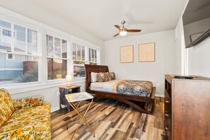 A bedroom with a wooden bed, a ceiling fan, and a desk. - Vintage Charming 1-bedroom house with WiFi and AC in welcoming Fort Worth. (Fort Worth)