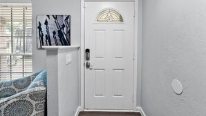 Una porta bianca con un pannello di vetro, un quadro appeso al muro e un cuscino decorato.