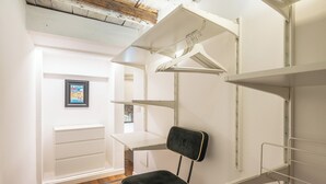 Ein Zimmer mit weißen Wänden, Holzboden und einem schwarzen Stuhl. Weiße Regale und ein weißer Schreibtisch sind ebenfalls vorhanden.