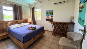 A bedroom with a bed, a chair, a desk, and a poster on the wall. - MOOREA - Waterfall Pool Coconut 1 (Pihaena)