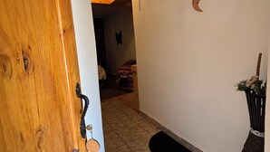 Ein Flur mit einer Holztür, gefliestem Boden, einer kleinen schwarzen Matte und einer Wand mit einer Monddekoration.