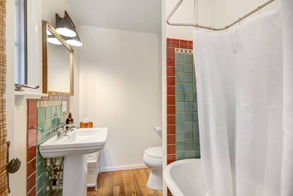 Une salle de bain avec un lavabo blanc, un miroir, des toilettes et une baignoire avec un rideau de douche.