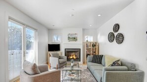 A modern living room with a fireplace, a flat-screen TV, and a sofa set.