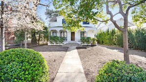 A two-story house with a front porch, a driveway, and a well-maintained garden.