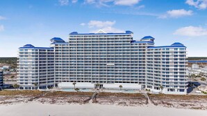 A large, multi-story hotel with a central atrium and balconies on each floor. - Lighthouse 1416 (Gulf Shores)