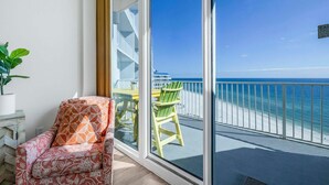 A balcony with a view of the ocean, a chair, and a potted plant. - Lighthouse 1416 (Gulf Shores)