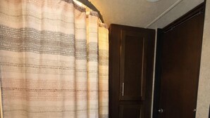 A compact bathroom with a shower curtain, a toilet, and a sink.